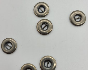 May include: Six antique gold-toned metal buttons with a circular shape and a single slit in the center.