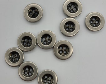 May include: Ten silver metal buttons with four holes each. The buttons have a slightly raised rim and a smooth, shiny surface.