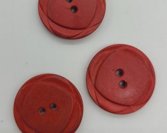 May include: Three red plastic buttons with two holes each. The buttons have a decorative design around the edges.