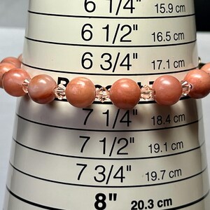 May include: A pink and clear beaded bracelet measuring 7 1/4 inches or 18.4 cm in circumference. The bracelet is made with round pink beads and clear crystal beads.