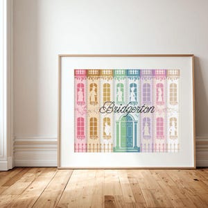 May include: Framed print featuring a colorful illustration of a building facade with arched windows and the word "Bridgerton" in script. The artwork is displayed in a wooden frame, set against a white wall and hardwood floor.