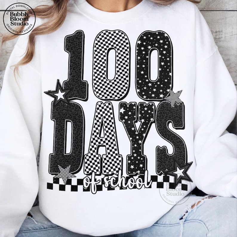 May include: White sweatshirt with a graphic design celebrating 100 days of school. The design features the numbers "100" with a checkered pattern, stars, and leopard print accents. The words "DAYS of school" are also included.