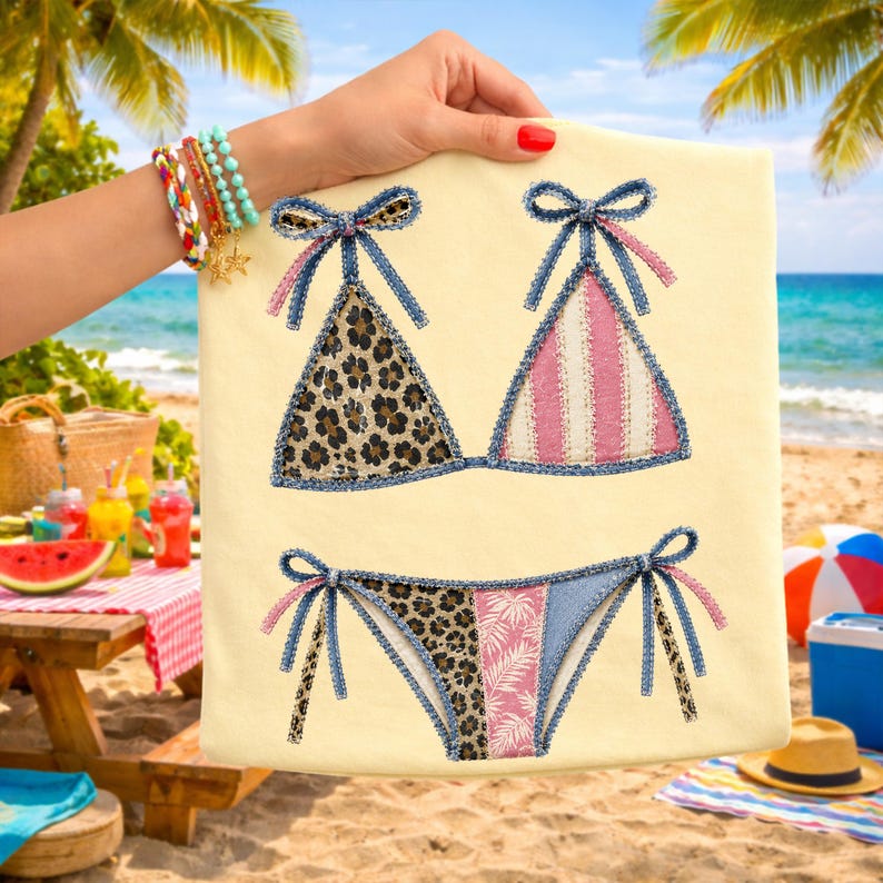 May include: A beige fabric featuring a bikini design. The bikini top has leopard print and pink and white stripes. The bikini bottom has leopard print and pink floral patterns. The edges are trimmed with denim and tied with denim bows.