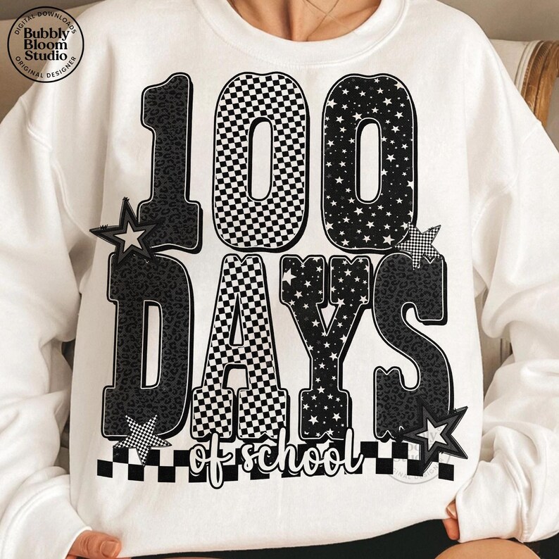 May include: White sweatshirt with a black and white graphic that reads "100 DAYS of school." The numbers and letters have various patterns, including leopard print, checkered, and stars. The design includes star accents.