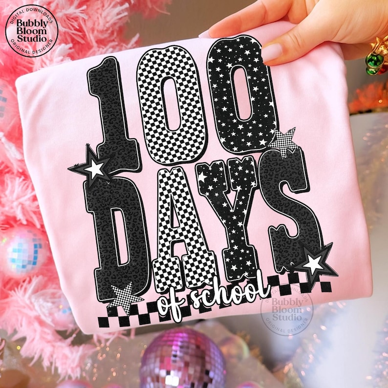 May include: A light pink t-shirt with the text "100 DAYS of school" in black, white, and gray checkered and star patterns. The shirt has star accents and the Bubbly Bloom Studio logo.