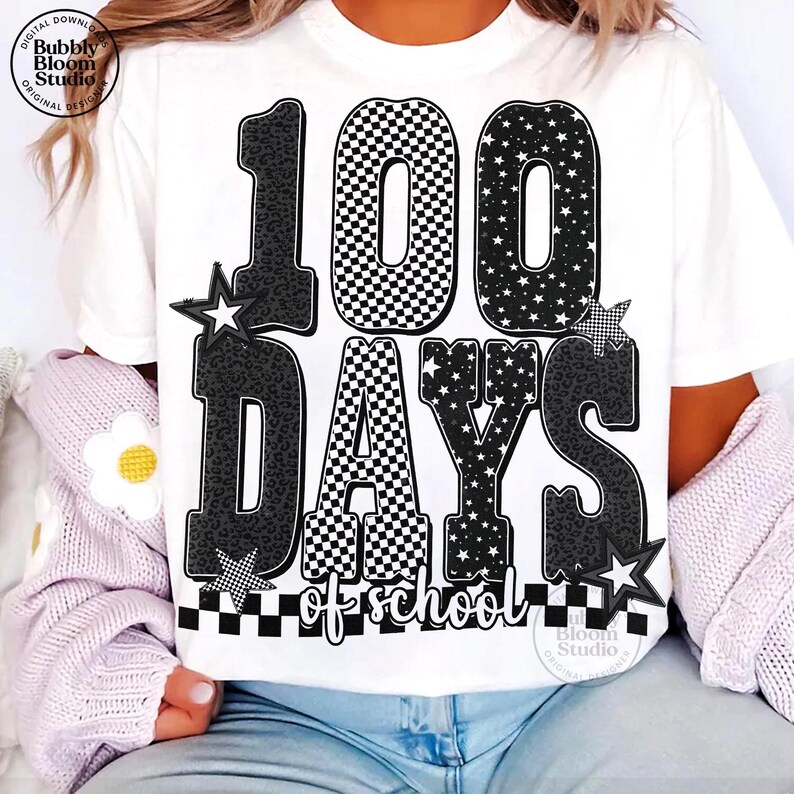 May include: White t-shirt with a graphic celebrating 100 days of school. The design features the number "100" with checkered and star patterns, along with the words "days of school". Black and white stars and a checkered border complete the design.