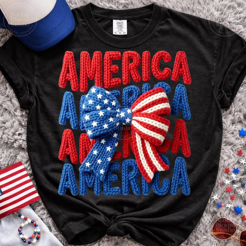 May include: Black t-shirt with the word "AMERICA" in red, white, and blue knitted letters. A knitted bow in red and white stripes and blue with white stars is centered on the shirt. Patriotic theme.