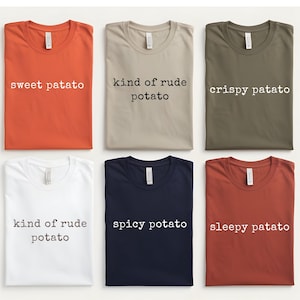 May include: Six t-shirts in various colors, each with a different potato-themed phrase in white text. Colors include orange, tan, olive green, white, navy blue, and rust. Phrases include "sweet patato", "kind of rude potato", "crispy patato", "spicy potato", and "sleepy patato".