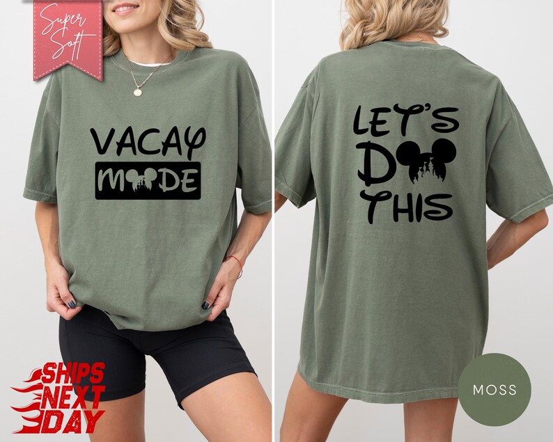 May include: A moss green t-shirt with the words "VACAY MODE" printed on the front in black. The back of the shirt says "LET'S DO THIS" with a Mickey Mouse silhouette. The shirt is a relaxed fit.