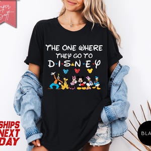 K&ouml;nnte beinhalten: Schwarzes T-Shirt mit dem Text "THE ONE WHERE THEY GO TO DISNEY" und Disney-Figuren. Das Shirt zeigt Goofy, Pluto, Minnie Mouse, Mickey Mouse und Donald Duck. Das Shirt hat auch die Worte "Super Soft" und "SHIPS NEXT DAY".