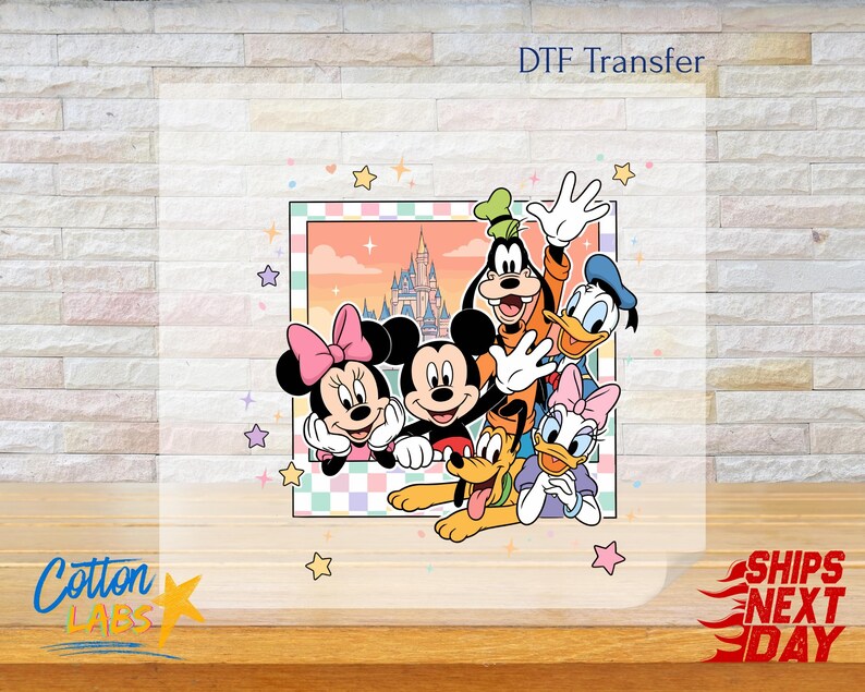Może przedstawiać: Transfer DTF z Myszka Miki, Myszka Minnie, Goofym, Kaczorem Donaldem, Daisy Duck i Pluto. Postacie są w kolorowej ramce z tłem zamku i gwiazdkami. Tekst "DTF Transfer" znajduje się u g&oacute;ry.
