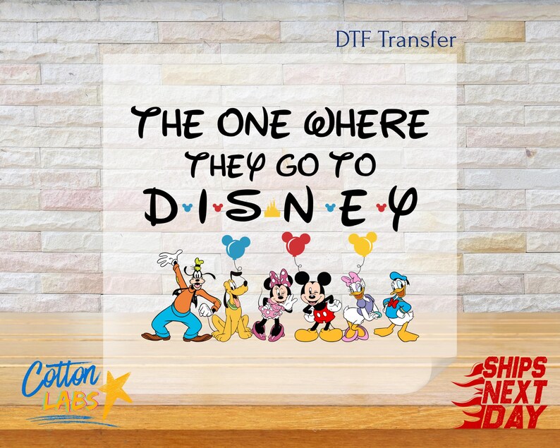 K&ouml;nnte beinhalten: Ein DTF-Transfer mit Disney-Figuren, darunter Goofy, Pluto, Minnie Mouse, Mickey Mouse, Daisy Duck und Donald Duck. Der Text lautet "The One Where They Go To Disney" in schwarzer Schrift. Ballons in Blau, Rot und Gelb sind enthalten.