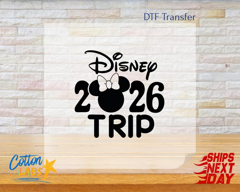 May include: Black and white graphic design featuring the word "Disney" above the number "2026" with a Minnie Mouse silhouette and the word "TRIP" below. The words "DTF Transfer" and "Cotton Labs" are also visible.