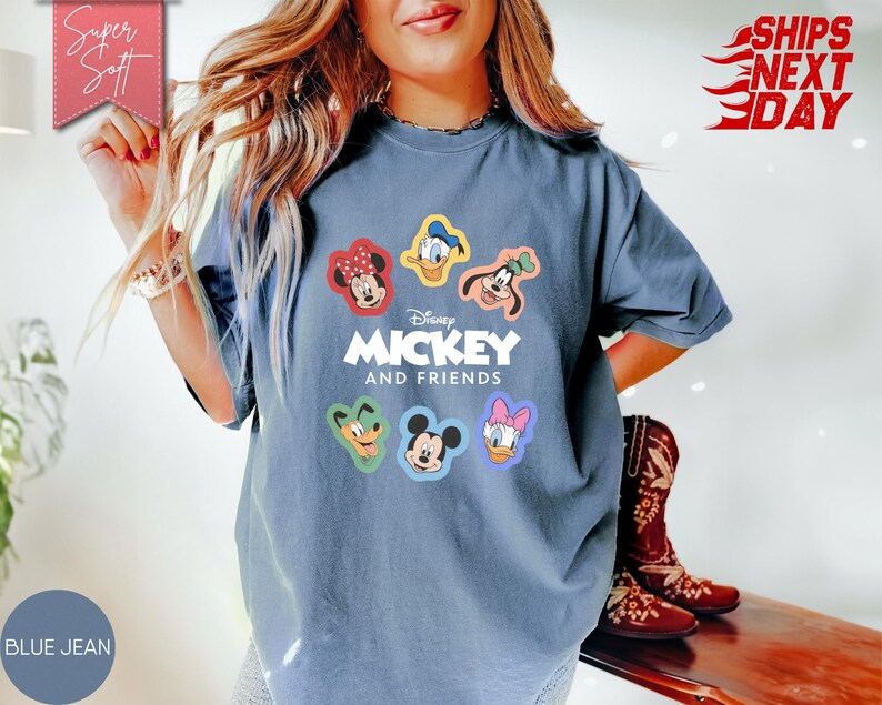 May include: Blue jean colored t-shirt featuring Disney's Mickey and Friends characters. The shirt has a crew neck and short sleeves. The graphic includes Mickey Mouse, Minnie Mouse, Donald Duck, Daisy Duck, Goofy, and Pluto. The text "Mickey and Friends" is printed below the characters.