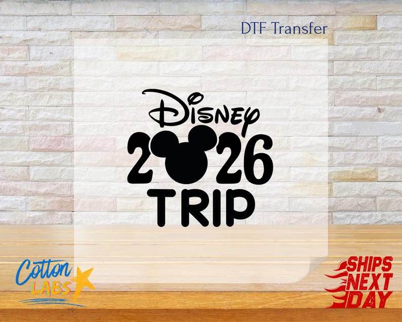 May include: Black graphic DTF transfer with the word "Disney" above the number "26" with a Mickey Mouse head silhouette, and the word "TRIP" below. The text "DTF Transfer" is at the top, and "Cotton Labs" is at the bottom left.
