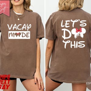May include: Espresso-colored t-shirt with "VACAY MODE" printed on the front and "LET'S DO THIS" on the back. The front design includes Mickey Mouse ears, and the back features a Mickey Mouse head with a red bow. The shirt is a soft, casual style.