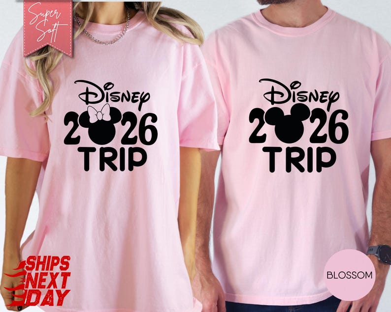 May include: Two light pink t-shirts with black text and graphics. One shirt features a Minnie Mouse design with a bow, the other a Mickey Mouse design. Both shirts read "Disney 2026 TRIP".