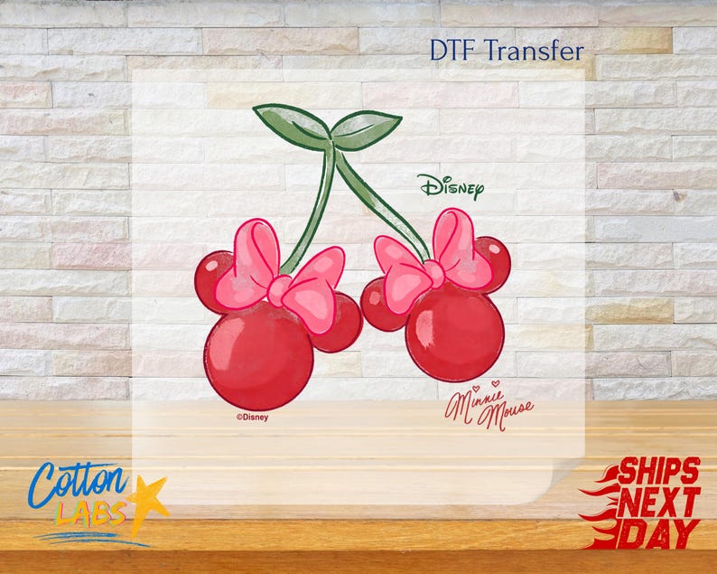 May include: DTF Transfer featuring a pair of red cherries with pink bows, designed in the style of Minnie Mouse. The image includes the Disney logo and the words "Minnie Mouse".