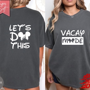 May include: Pepper-colored t-shirts with white text. One shirt reads "VACAY MODE" with a Mickey Mouse silhouette. The other shirt says "LET'S DO THIS" with a Mickey Mouse silhouette. The shirts are soft and comfortable.