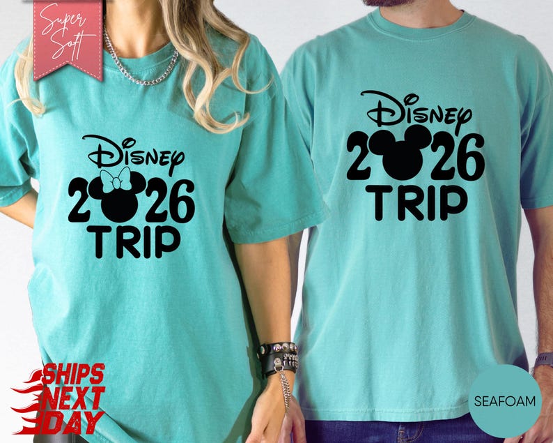 May include: Two teal-colored t-shirts with the text "Disney 2026 TRIP" in black. One shirt has a Minnie Mouse bow graphic, the other has a Mickey Mouse graphic. The shirts are made of a soft material.