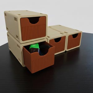 Könnte beinhalten: Stapelbare beige und braune Aufbewahrungsschubladen. Die Schubladen haben eine geriffelte Vorderseite und einen gebogenen Griff. Eine Schublade ist geöffnet und zeigt einen grünen und schwarzen Gegenstand. Die Schubladen stehen auf einer dunklen Oberfläche.