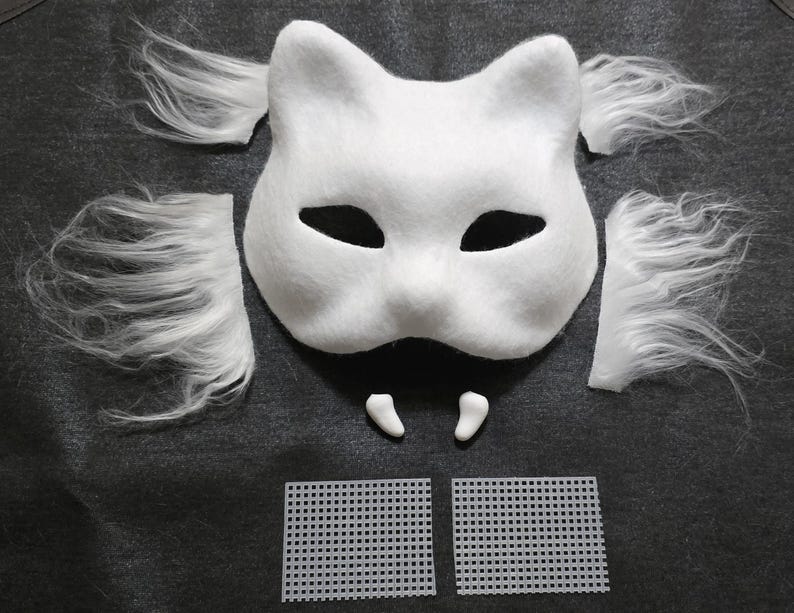 May include: A white cat-shaped mask with pointed ears and black eye cutouts, accompanied by four separate pieces of white faux fur, two small white fangs, and two rectangular pieces of white plastic mesh grid for crafting and assembly.
