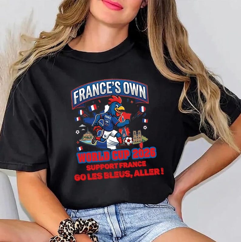 A woman wearing a black t-shirt with a graphic design featuring a cartoon rooster and text promoting France's participation in the World Cup.