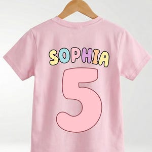 A pink t-shirt with the name "Sophia" and the number "5" printed on it.