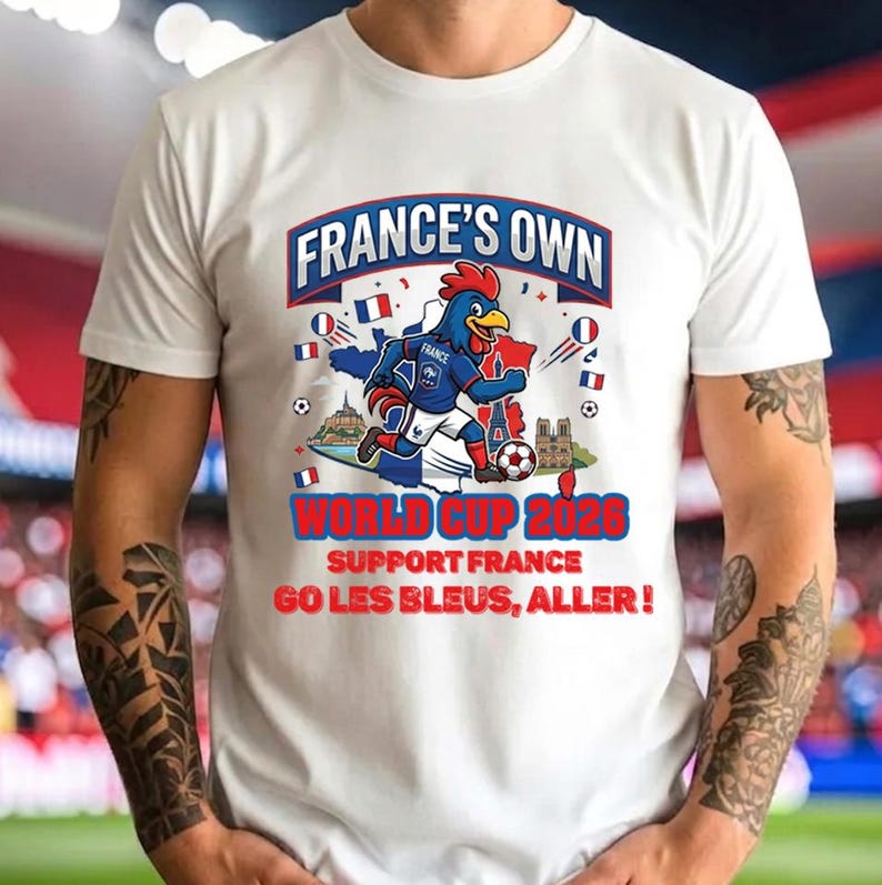 A white t-shirt with a graphic design featuring a cartoon rooster holding a soccer ball, surrounded by various flags and text related to the World Cup in France.