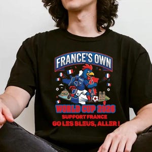 A person wearing a black t-shirt with a graphic design featuring a rooster and the text "FRANCE'S OWN WORLD CUP 2026 SUPPORT FRANCE GO LES BLUES, ALLER!"