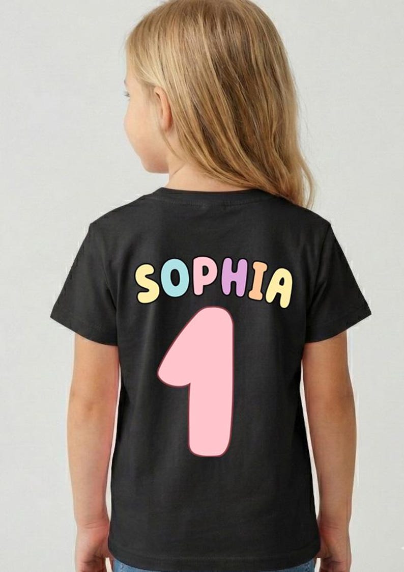 A young girl wearing a black t-shirt with the name "Sophia" and the number "1" printed on it.