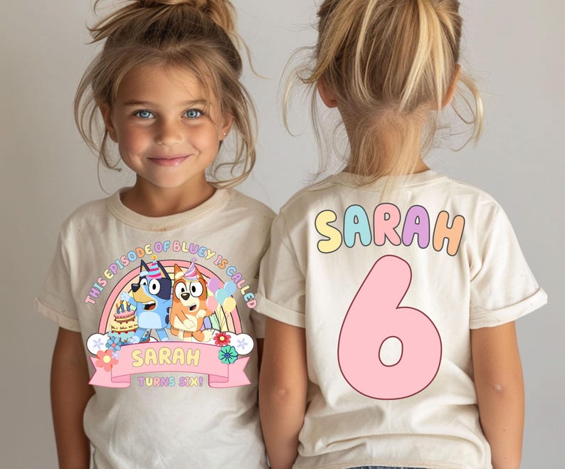two young girls wearing white t-shirts with a birthday-themed design.