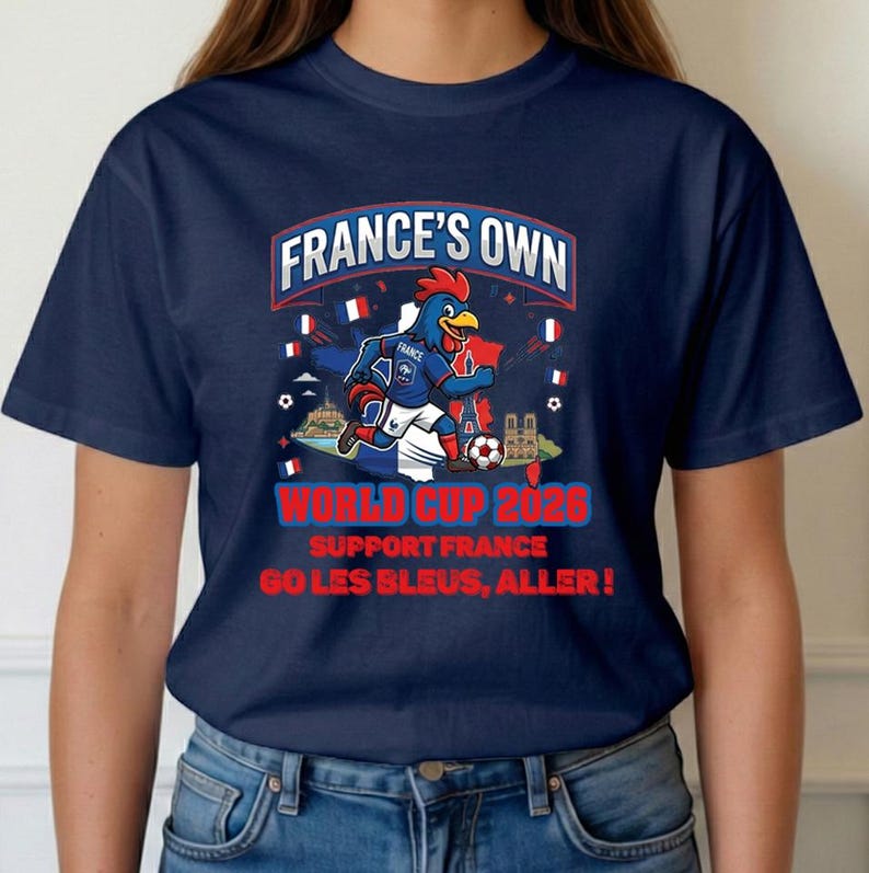 A blue t-shirt with a graphic design featuring a cartoon rooster and various French-themed elements, along with text promoting the French national team's participation in the World Cup.