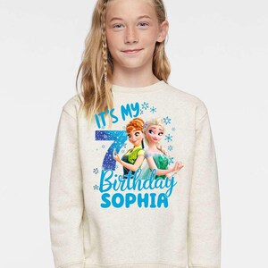 a young girl wearing a sweatshirt with a frozen princess image on it