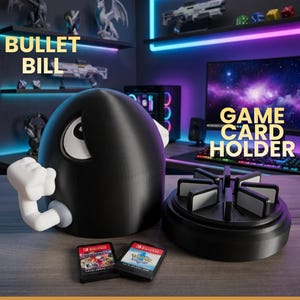 Può includere: Un porta schede di gioco Bullet Bill nero con un braccio e un occhio bianchi. Il supporto include una base circolare con fessure per diverse cartucce di gioco. Due cartucce di gioco sono posizionate davanti al supporto sulla superficie.
