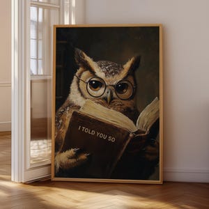 May include: A framed print featuring a detailed illustration of an owl wearing glasses and reading a book. The book is open, displaying the text "I told you so". The owl has brown and white feathers and is set against a dark background.