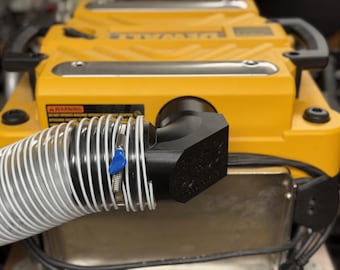 May include: A yellow and black power planer with a clear and white flexible hose attached. The hose is secured with a metal clamp and a blue handle. The planer has black handles and a warning label.