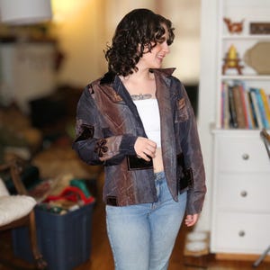 Peut inclure: Veste patchwork aux tons marron et bleu, avec des détails en velours noir. La veste a un col et est portée avec un jean bleu.