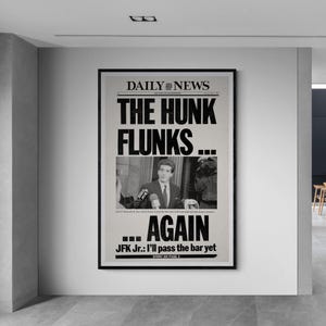 May include: A framed black and white print of a newspaper front page. The headline reads "THE HUNK FLUNKS...AGAIN". A photograph of a man in a suit is below the headline. The newspaper is titled "DAILY NEWS".
