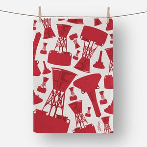 May include: A white towel with a repeating pattern of red buoy illustrations. The buoys vary in size and shape, with some featuring a tower-like structure. The towel is hanging from a clothesline with wooden clothespins.