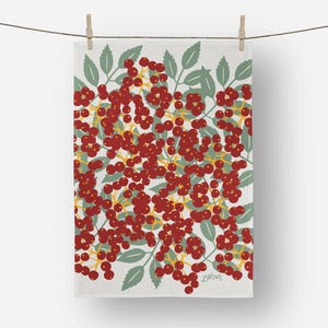 May include: A white kitchen towel with a botanical design. The pattern features clusters of red berries, green leaves, and yellow stems. The towel is hanging from a clothesline with wooden clothespins.