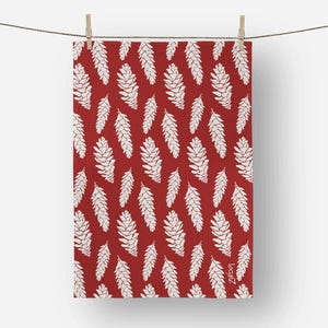 May include: A red and white patterned textile featuring a repeating design of stylized pine cones. The pine cones are white and arranged against a solid red background. The textile is hanging from a clothesline with wooden clothespins.