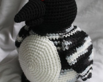 May include: A crocheted penguin stuffed animal with black and white stripes, a white belly, and red eyes.