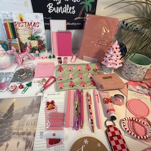 Könnte beinhalten: Eine Sammlung von Schreibwaren und weihnachtlichen Artikeln, darunter ein Weihnachtsmalbuch, ein rosa Notizbuch, eine Keramiktasse mit Glühbirnenmuster, ein Korkuntersetzer mit dem Wort Joy, Stifte, eine Handcremetube und verschiedene rosa Accessoires.