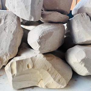 May include: A pile of irregularly shaped, light beige chalk rocks. The chalk pieces have rough, textured surfaces and varying sizes, with visible cut marks. The overall arrangement suggests a natural, raw material.
