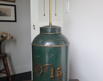 May include: Vintage green metal lamp with a cylindrical base and three light sockets. The lamp features the number "15" in gold script on the front. The lamp has a dark wooden base and a green glass finial.