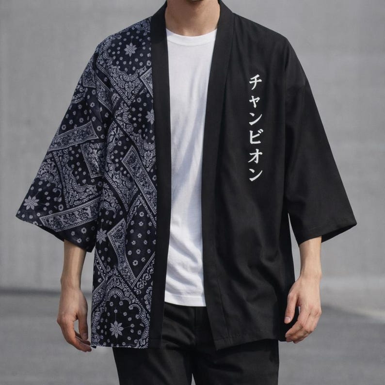 May include: Black and navy blue kimono-style jacket. The left side features a navy blue paisley pattern, while the right side is solid black with white Japanese text. The jacket has three-quarter sleeves and a relaxed fit.