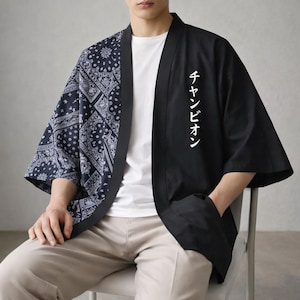 May include: Black and navy blue kimono-style jacket. The left side features a navy blue paisley pattern, while the right side is solid black with white Japanese text. The jacket has wide sleeves and is open in the front.