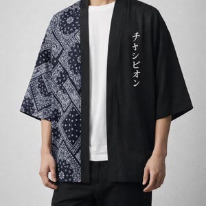 May include: Black and navy blue kimono-style jacket. The left side features a navy blue paisley pattern, while the right side is solid black with white Japanese text. The jacket has wide sleeves and a relaxed fit.