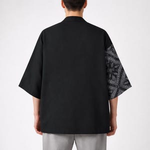 May include: Black short-sleeved shirt with a contrasting paisley pattern on the right sleeve. The shirt has a classic collar and a relaxed fit. The paisley pattern is in shades of gray and white.